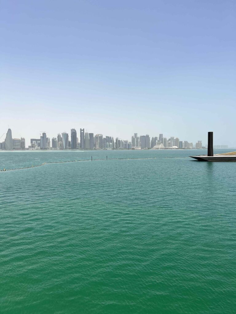 Image of tall city buildings in the distance with blue-green water in the foreground